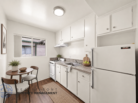 A kitchen with white cabinets and a refrigerator.