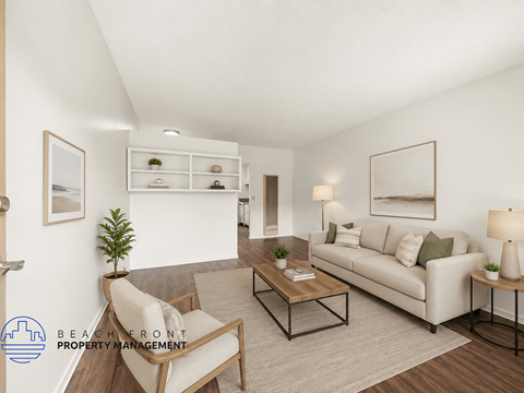 A living room with a white couch, a chair, a coffee table, and a plant.