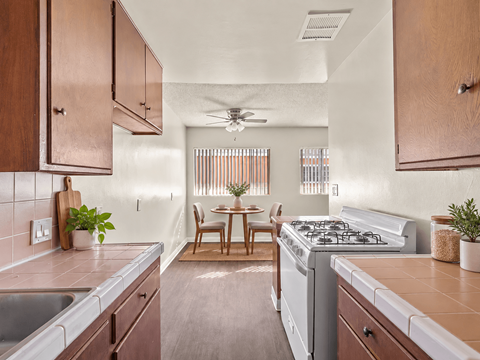 A kitchen with a stove, sink, and dining table.