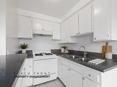A kitchen with white cabinets and a black countertop.