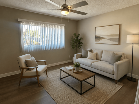 A living room with a white couch, a chair, a coffee table, and a ceiling fan.