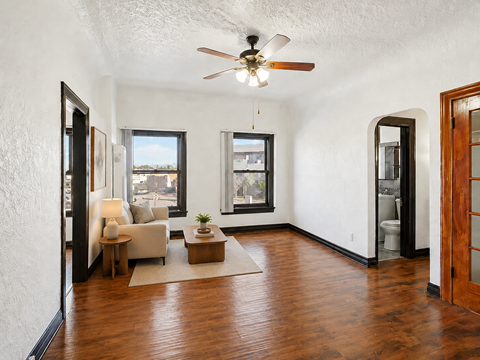 A living room with a ceiling fan and hardwood floors.