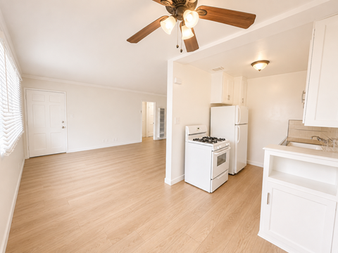 A kitchen with white appliances and wooden floors.