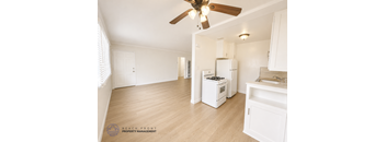 A kitchen with a fan and wooden floors.