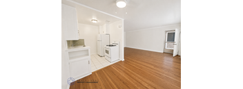 A kitchen with white appliances and wooden floors.