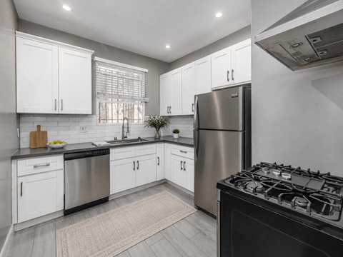 A modern kitchen with white cabinets and stainless steel appliances.