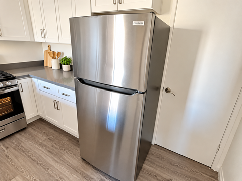 A stainless steel refrigerator in a kitchen with white cabinets.