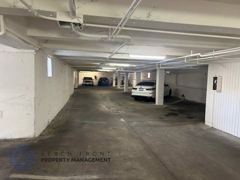 A parking garage with a few cars and a logo that says "Beach Front Property Management".