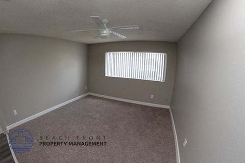 an empty room with a ceiling fan and a window