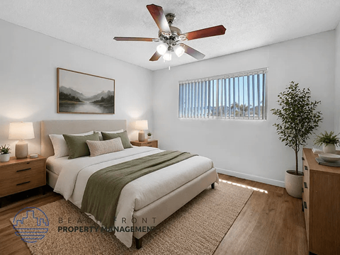 A bedroom with a bed, nightstands, a ceiling fan, and a painting on the wall.