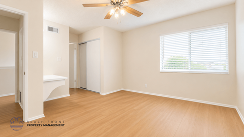 A spacious room with a ceiling fan and a window with blinds.