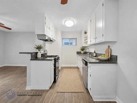 A kitchen with white cabinets and a black countertop.