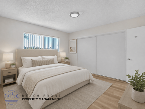 A bedroom with a large bed, a nightstand with lamps, a window with blinds, a rug, a potted plant, and a sliding door.