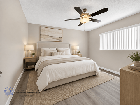 A bedroom with a large bed and a ceiling fan.
