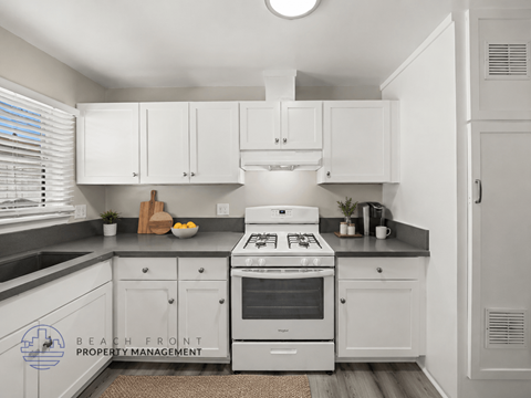 A kitchen with white cabinets and a stove top oven.