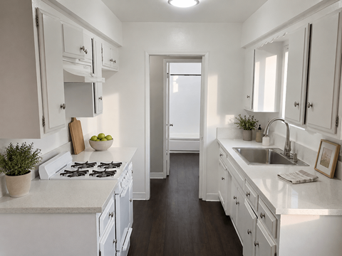 A white kitchen with a stove, sink, and cabinets.