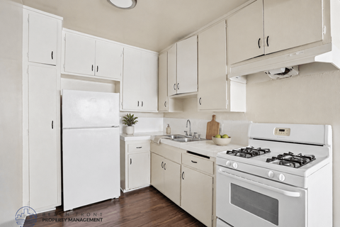 A white kitchen with a refrigerator, oven, and sink.