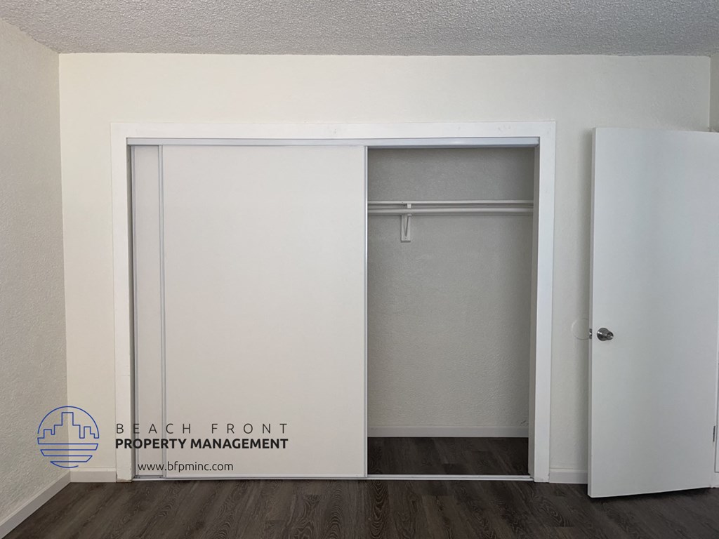 a sliding door closet in a room with white walls and a wood floor