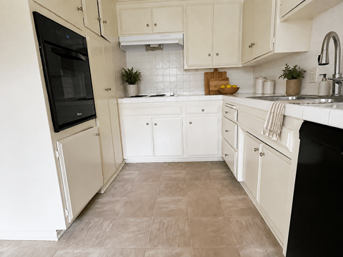 A kitchen with white cabinets and a black fridge.