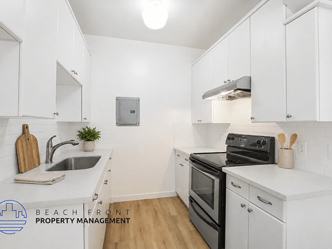 A kitchen with white cabinets and a black stove top oven.