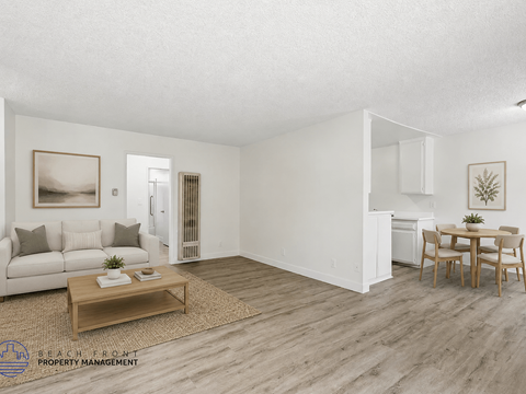 A living room with a white couch, a coffee table, and a dining table with chairs.