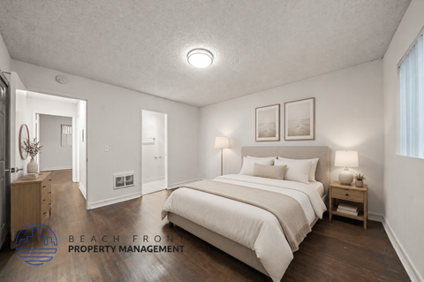 A bedroom with a large bed and a nightstand with a lamp.