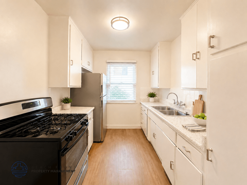 A kitchen with a black stove top oven and white cabinets.