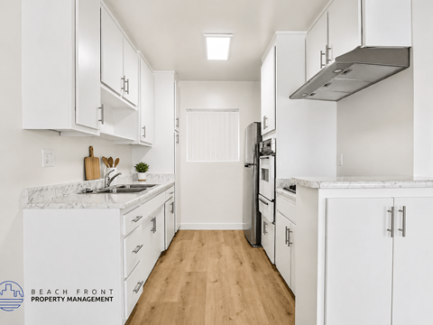 A kitchen with white cabinets and a marble countertop.