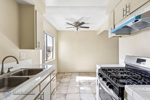 A kitchen with a stove top oven and a sink.