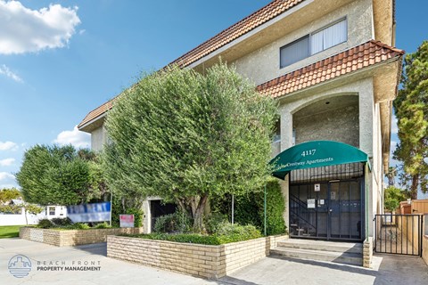 A building with a green awning and the words "4111 Beachfront Apartments" written on it.