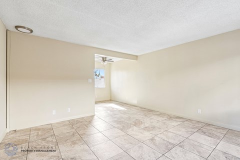 A spacious room with tiled flooring and a ceiling fan.