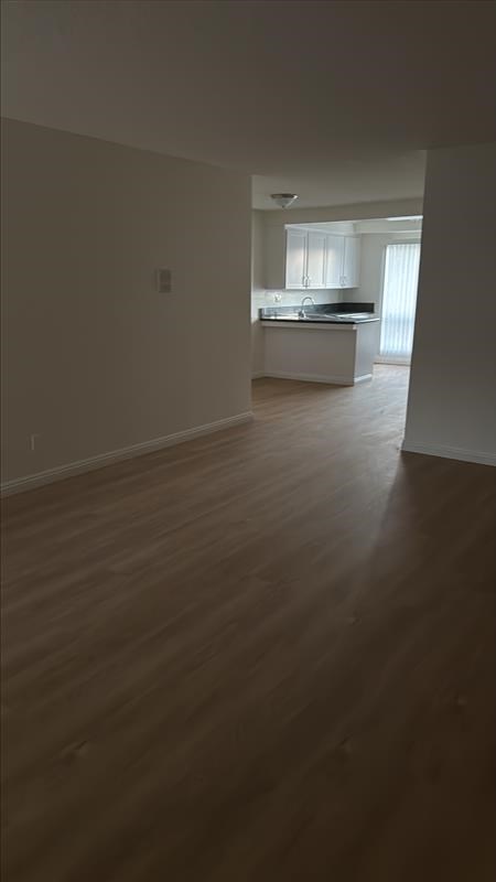 A kitchen with a sink and a window is visible through the doorway.