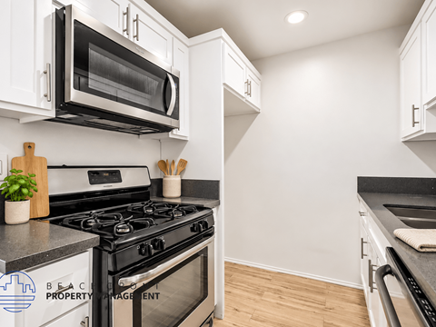 A modern kitchen with a black stove top oven and white cabinets.
