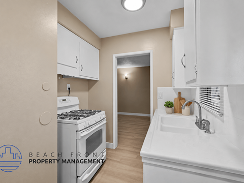 A kitchen with a stove, sink and cabinets.