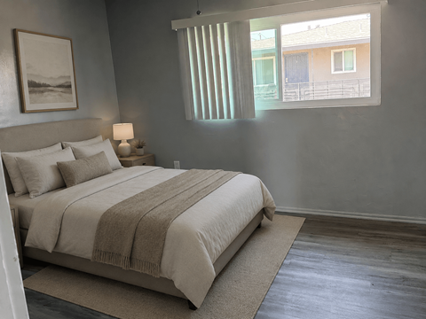 A bedroom with a bed, lamp, and a painting on the wall.