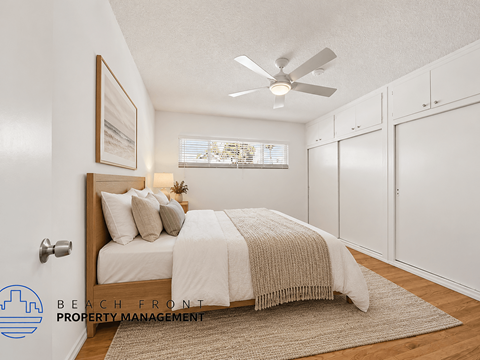 A bedroom with a bed, a ceiling fan, and a rug on the floor.