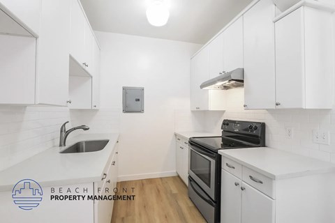 A kitchen with white cabinets and a black stove top oven.