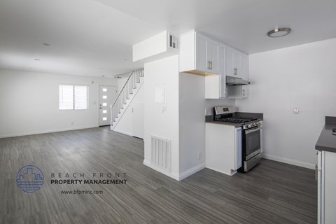 a renovated kitchen with white cabinets and a stove and a staircase