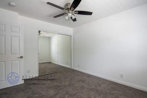 a bedroom with a ceiling fan and a closet