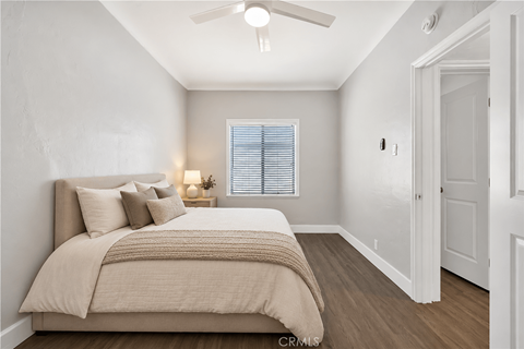 A bedroom with a bed, pillows, a blanket, a ceiling fan, and a window with blinds.