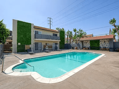 A small residential building with a green wall and a pool in front.