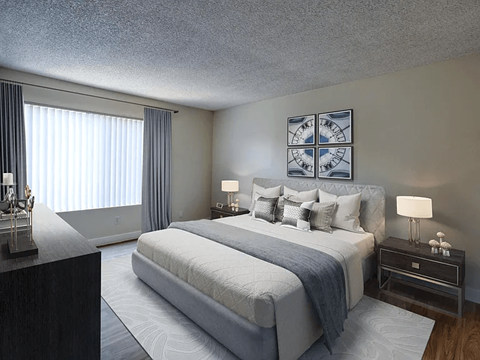 A bedroom with a large bed and a nightstand with a lamp.