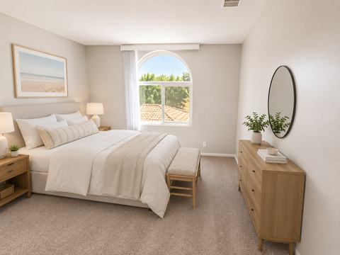 A bedroom with a large bed, a nightstand, and a window overlooking a deck.