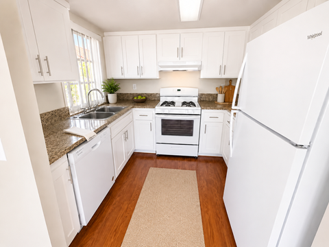 A kitchen with white appliances and wooden floors.
