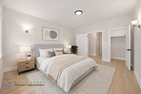 A well-lit bedroom with a large bed and a nightstand with a lamp.