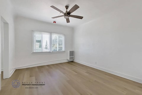 A room with a ceiling fan and a window with blinds.