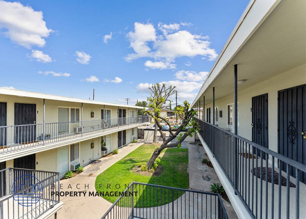 a courtyard of apartments with balconies and a tree in the yard