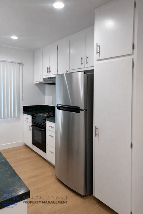 A modern kitchen with a stainless steel refrigerator and white cabinets.