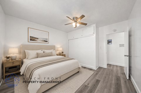 A bedroom with a bed, nightstand, and a ceiling fan.