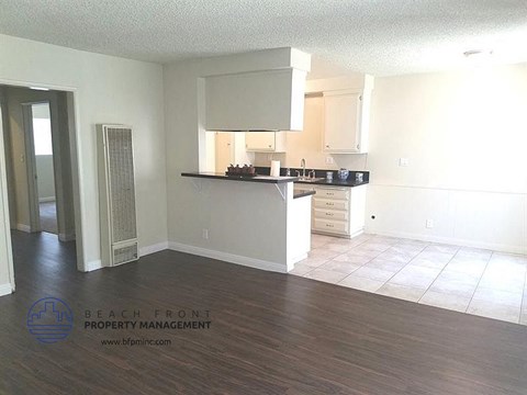 an empty kitchen with white cabinets and a wooden floor